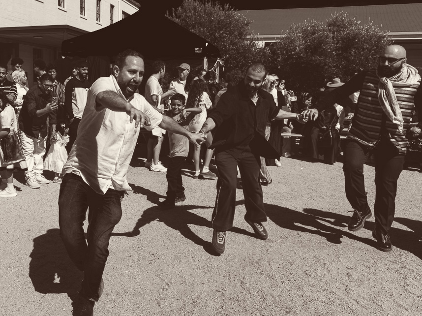 Community members dancing dabke together at an outdoor gathering.